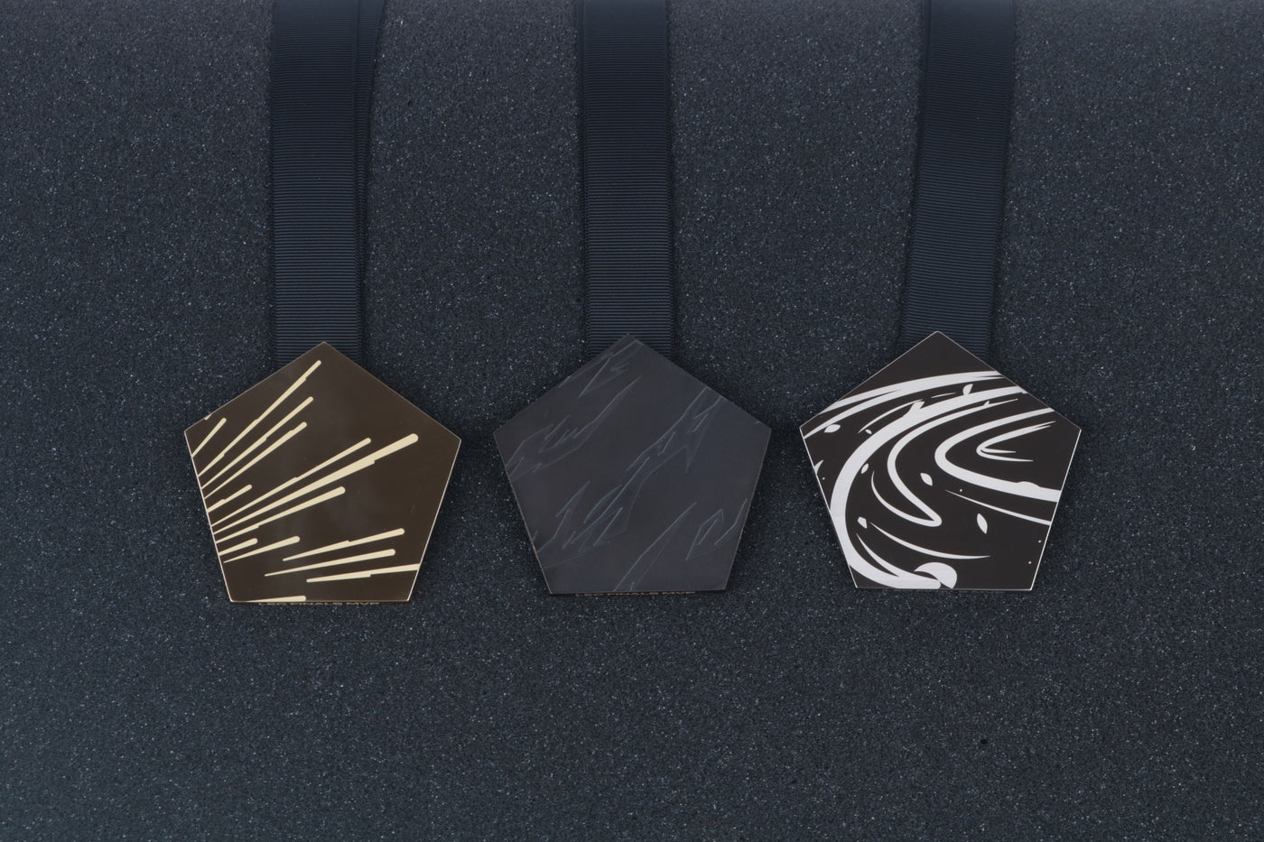 three medals on a black backdrop in chrome and anodized finish with etched text and graphics