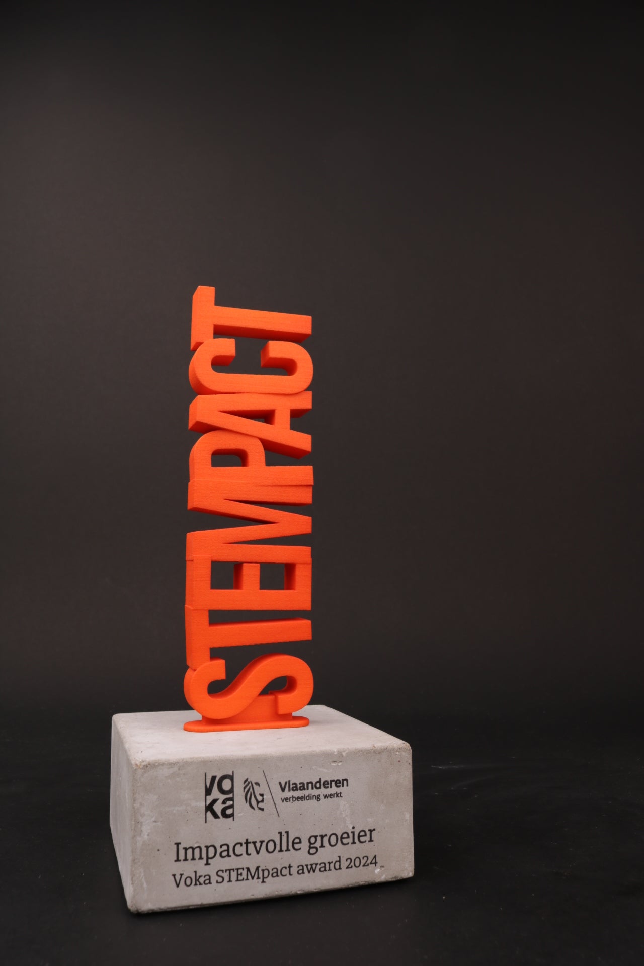 a concrete base with an orange 3d printed text on top