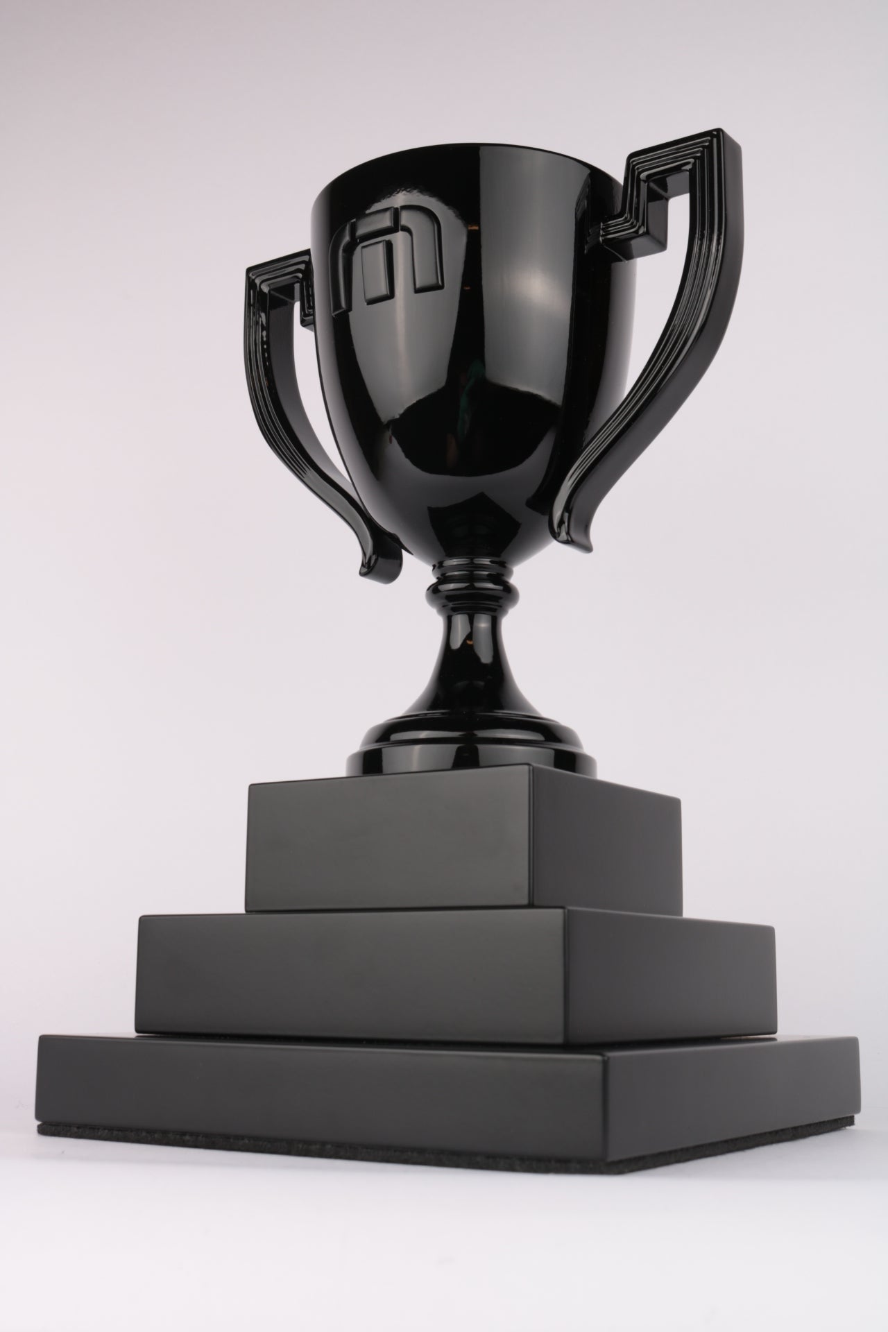 glossy black trophy cup on stepped matte black base