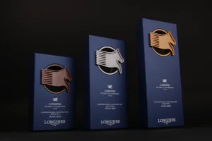 Three navy Global Champions Jumping sports trophies with bronze, silver and gold horse heads for Longines