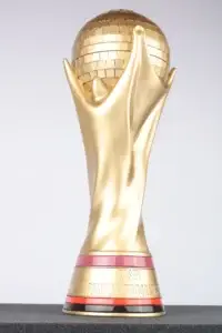 Gold Casey Trophy of two hands holding a globe on a red banded base