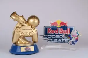 Trophée doré d'une chaussure de football sur un ballon et une manette de jeu à côté d'un panneau acrylique Red Bull Coded Cleats