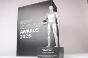 BMW Motorrad Awards 2025 trophy with a silver rider figure holding a helmet in front of a black and grey panel