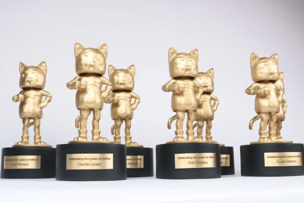 Gold cat figurine awards on black bases for the five year anniversary of AdHoc