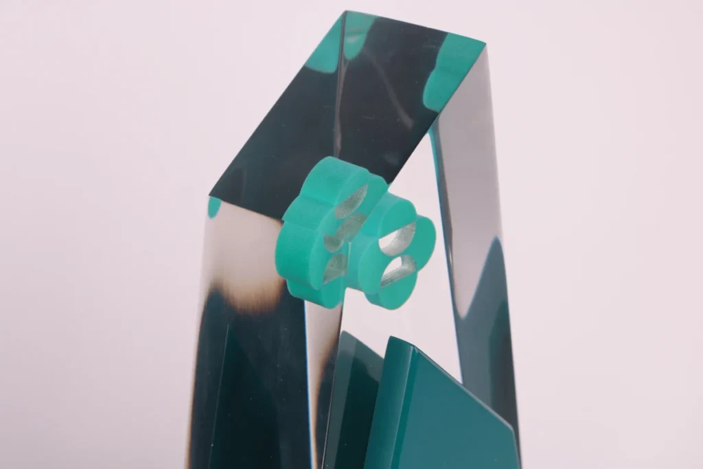 Close-up of a clear acrylic Power of Purpose award with embedded teal logo