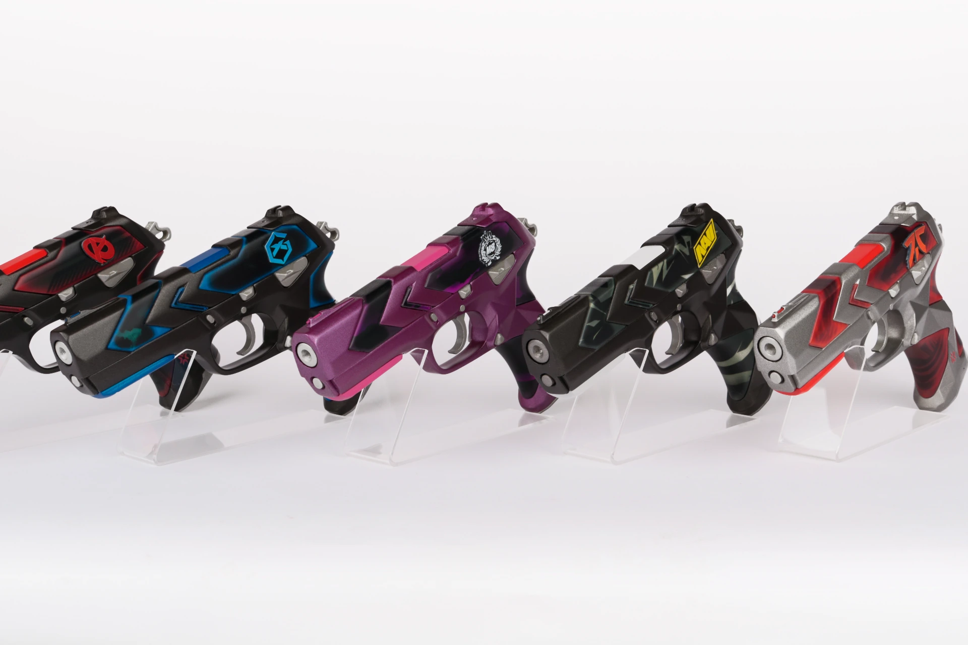 Five VCT EMEA team Classic pistol props on acrylic stands, each finished in its team colour palette